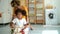 Mom and daughter play at home while doing laundry Spbd. little girl is driving in clothes basket