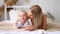 mom and daughter play, hug and kiss at home on the bed, lifestyle, tender relationship of a young mother and child