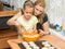 Mom and daughter seven years pour batter into the mold for baking muffins