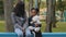 Mom and daughter sitting on bench child holding teddy bear little girl showing five fingers african american family