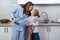 mom and daughter together in the kitchen wipe the dishes with towels. look at each other and kiss. parenting help