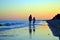 Mom and daughter walking on the empty peaceful sea beach at suns