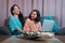 Mom and daughter watching a laptop sitting on the sofa at home, the two make expressions when looking at their computer