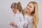 Mom and daughter in white shirts with long blonde hair posing on a solid background in the Studio. a charming family takes care of