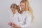 Mom and daughter in white shirts with long blonde hair posing on a solid background in the Studio. a charming family takes care of