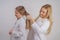 Mom and daughter in white shirts with long blonde hair posing on a solid background in the Studio. a charming family takes care of