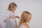 Mom and daughter in white shirts with long blonde hair posing on a solid background in the Studio. a charming family takes care of