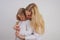 Mom and daughter in white shirts with long blonde hair posing on a solid background in the Studio. charming family takes care of e