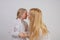 Mom and daughter in white shirts with long blonde hair posing on a solid background in the Studio. charming family takes care of e