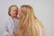 Mom and daughter in white shirts with long blonde hair posing on a solid background in the Studio. charming family takes care of e