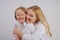 Mom and daughter in white shirts with long blonde hair posing on a solid background in the Studio. charming family takes care of e