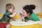 Mom with dreadlocks and her little son playing on the bed with t