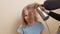 mom dries her daughter's hair with a hair dryer with a comb attachment.