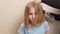 mom dries her daughter's hair with a hair dryer with a comb attachment.