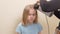 mom dries her daughter's hair with a hair dryer with a comb attachment.