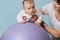 Mom is engaged in exercises with her infant son, on a fitness ball