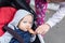 Mom feeding baby boy with bread crust outdoor. Child sitting in stroller during walk and tasting bread for first time. Lemon face