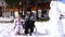 Mom feeds a little girl with porridge from a spoon while sitting on a sled near a snowman