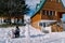 Mom feeds little girl from a spoon sitting on a sled in the courtyard of a wooden chalet