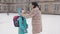 Mom in a fur coat in winter, meets a little girl near the school building after school.