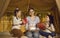 Mom gives birthday gifts to her twin daughters and a cake sitting in a cozy bed tent.