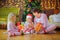 Mom gives gifts to children sitting on the floor near the festive Christmas tree