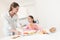 Mom gives her daughter breakfast. They are in the bright kitchen.