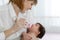 Mom giving baby water from the bottle sitting on the bed