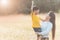 Mom is happily carrying her son in the meadow. Asian young mother and her little child at sunset. Soft focus