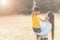 Mom is happily carrying her son in the meadow. Asian young mother and her little child at sunset. Soft focus