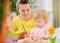 Mom helping baby painting on Easter eggs