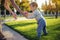 Mom helps cute baby walking on a green lawn in nature on a Sunny autumn day. Concept first child steps