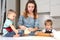 Mom helps young sons knead the dough on the kitchen table