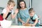 Mom helps young sons knead the dough on the kitchen table