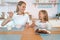 Mom with her daughter eating chocolate flakes. they hold spoons at their mouth and look at each other and smile. have a good time