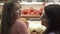 Mom with her daughter in the store on a background of shelves with tomatoes