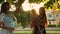 Mom and her daughters blow big soap bubbles in evening city park at sunset. Children and mother play together and laugh