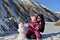 Mom and her little daughter in the winter sculpt a snowman in the mountains.