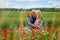 Mom with her son in a magnificent meadow. The boy surprised her mother with red poppies.