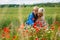 Mom with her son in a magnificent meadow. The boy surprised her mother with red poppies.