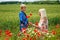 Mom with her son in a magnificent meadow. The boy surprised her mother with red poppies.