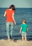 Mom and her son on walk by sea on summer beach. Motherhood and childhood concept