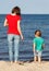 Mom and her son on walk by sea on summer beach. Motherhood and childhood concept