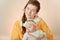 Mom holds the baby in her arms and poses for the camera in the studio, the concept of love and unity and care for loved ones and