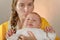 Mom holds the baby in her arms and poses for the camera in the studio, the concept of love and unity and care for loved ones and