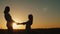 Mom holds her daughter`s hands, stand alone at sunset. Single parent concept