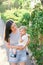 Mom holds a little girl in her arms near the fence entwined with ivy