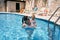Mom holds a little whimpering girl in her arms in the pool
