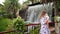 Mom hugs baby and looks at the camera on the background of a waterfall and palm trees