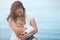 Mom hugs her little son kissing her tightly and lovingly against the background of the sea